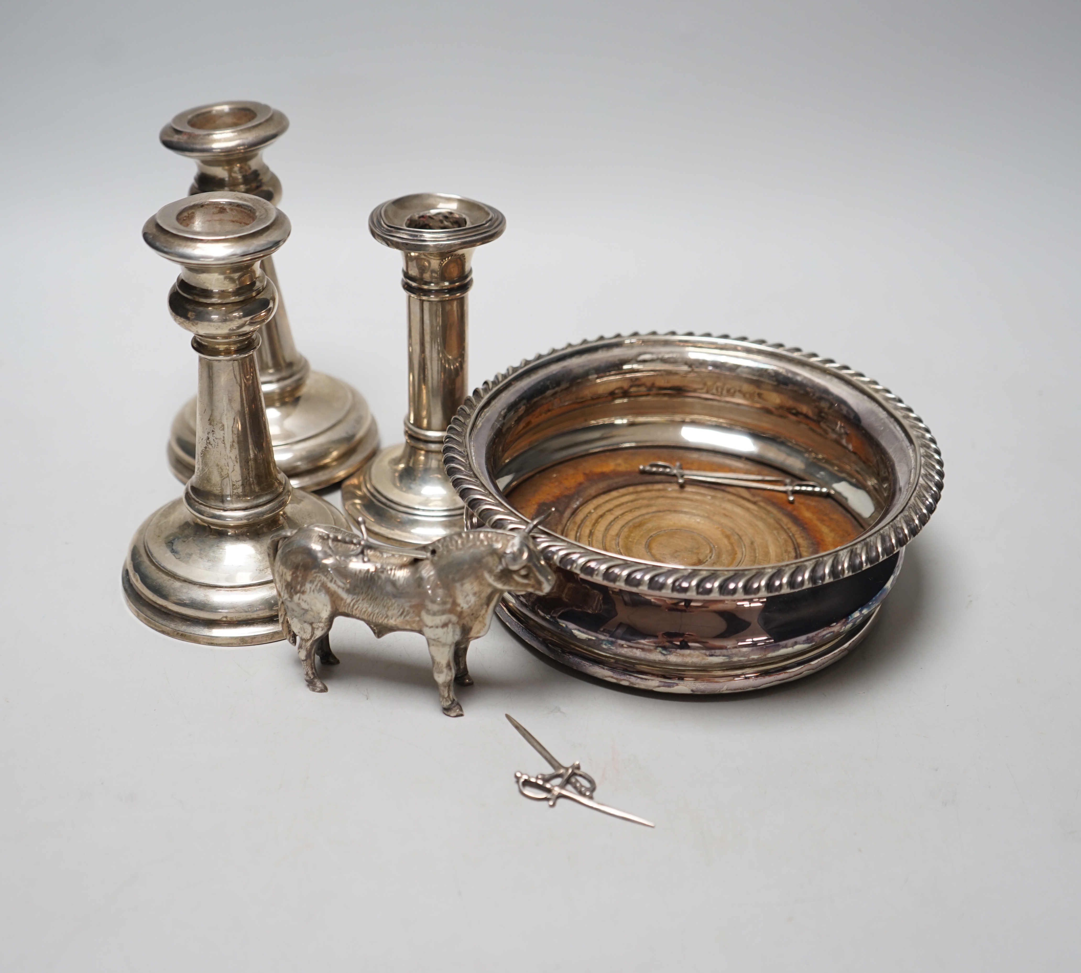 A pair of early 20th century silver mounted dwarf candlesticks, marks rubbed, height 13.2cm (a.f.), one other silver mounted dwarf candlestick, a late Victorian silver mounted wine coaster, London, 1894 and a novelty whi